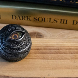 One "Black Eye Orb" prop replica, sitting on a wooden box with a "Dark Souls" Design Works book stacked in the background.