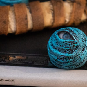 Single "Blue Eye Orb" Dark Souls prop, sitting on a Design Works book with an obscured Straight Sword hilt prop visible in the background.