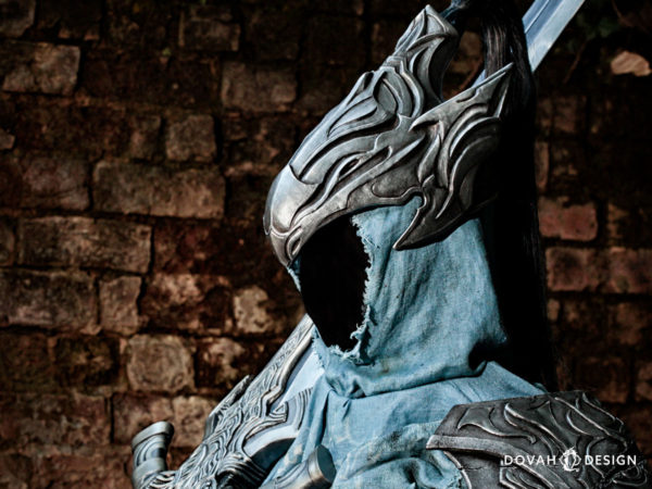 Sam wearing her full Knight Artorias cosplay, facing left and posed with greatsword. Helm of Artorias is centered in view.