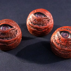 Group of three red eye orb prop replicas, sitting on black background.