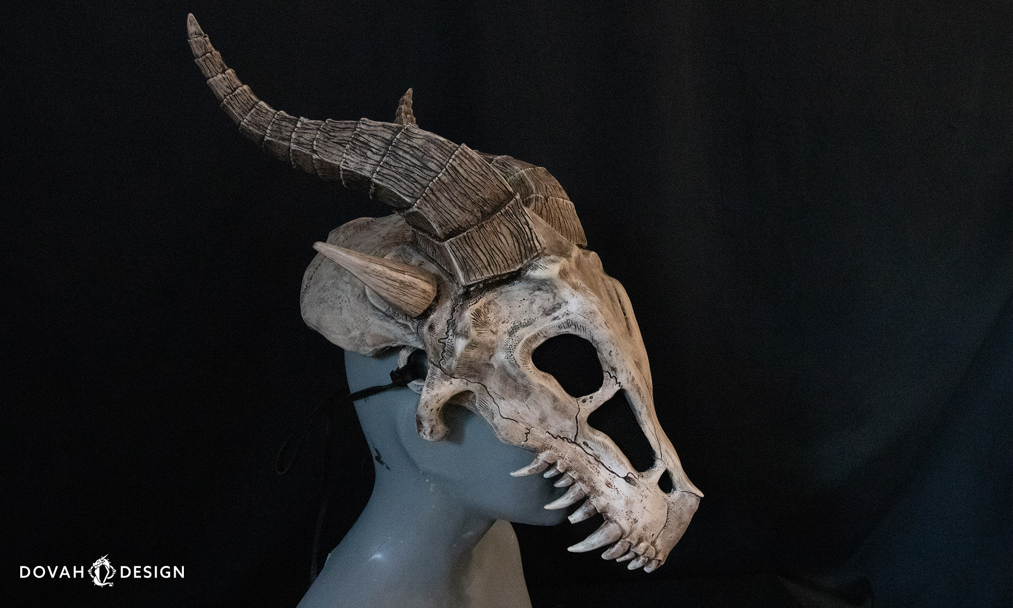 Wearable dragon skull helmet prop posed in profile on a gray mannequin in front of a black background.