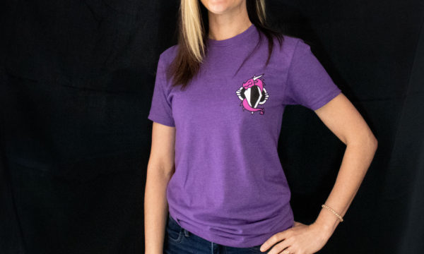 Close up of the purple dovah design t-shirt worn by Sam, posing with hand on hip in front of a black background.