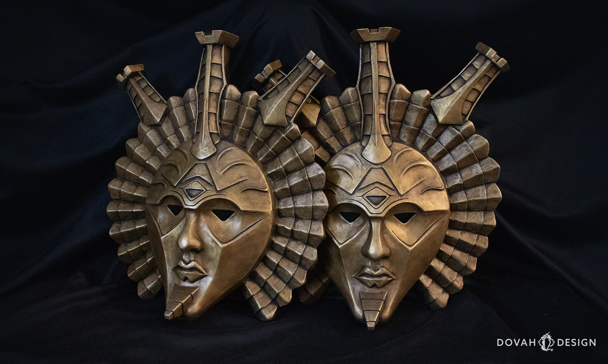 Two Dagoth Ur mask replicas, sitting upright on a table wit a black background.
