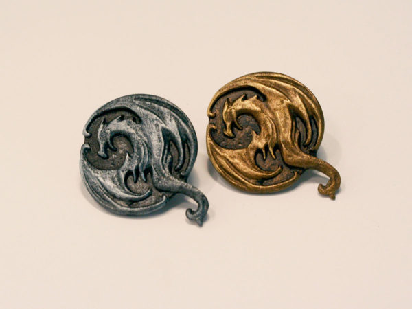 Shiny steel and gold lapel pins, cast in resin, of the Elder Scrolls Online Elsweyr logo. Both sitting side by side on a white background.