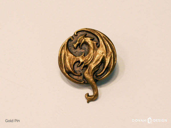 Shiny gold lapel pin, cast in resin, of the Elder Scrolls Online Elsweyr logo. Close up detail of the dragon logo.