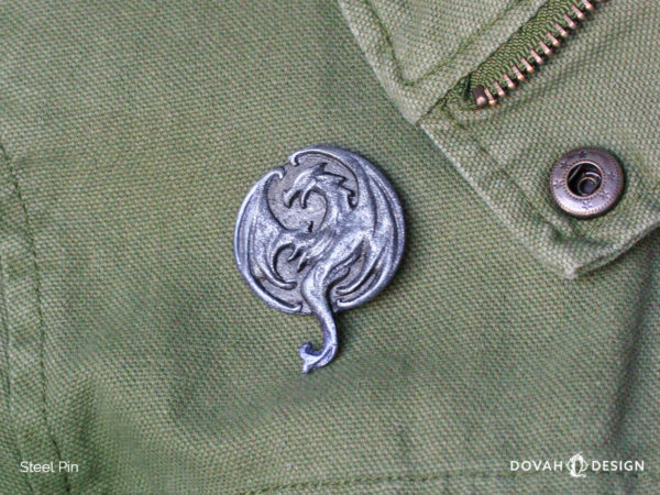 Elsweyr dragon logo lapel pin, pinned on a green cotton jacket for scale, close up detail shot of the cast resin pin.