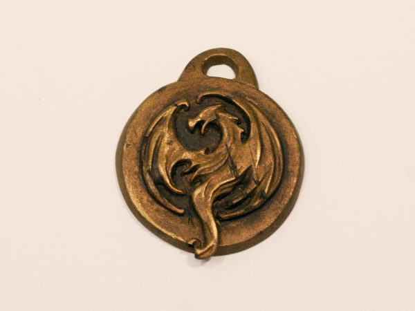 Distressed bronze pendant of the Elder Scrolls Online Elsweyr logo.