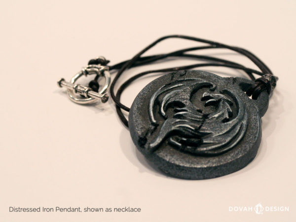 Distressed iron necklace of the Elder Scrolls: Online Elsweyr logo. Shown as a necklace, keyring, lying flat. Logo depecits a drake (dragon) symbol, purposely aged to look like old treasure.