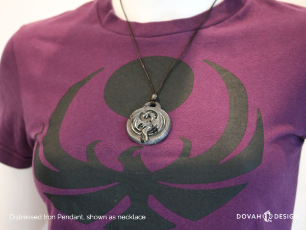 Distressed iron necklace of the Elder Scrolls: Online Elsweyr logo. Shown as a necklace on display mannequin. Logo depecits a drake (dragon) symbol, purposely aged to look like old treasure.