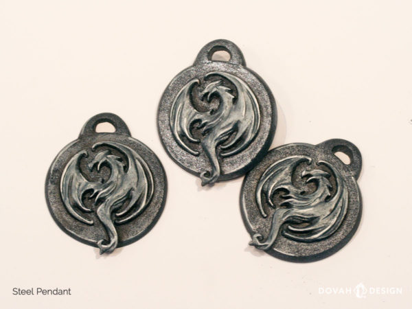 Pendant of the Elder Scrolls Online Elsweyr logo in steel color. Three pendants shown lying flat. Logo depecits a drake formed in a circle.