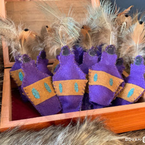 Box of handmade skooma bottle cat toys, posed in an open box on top of fur blanket.