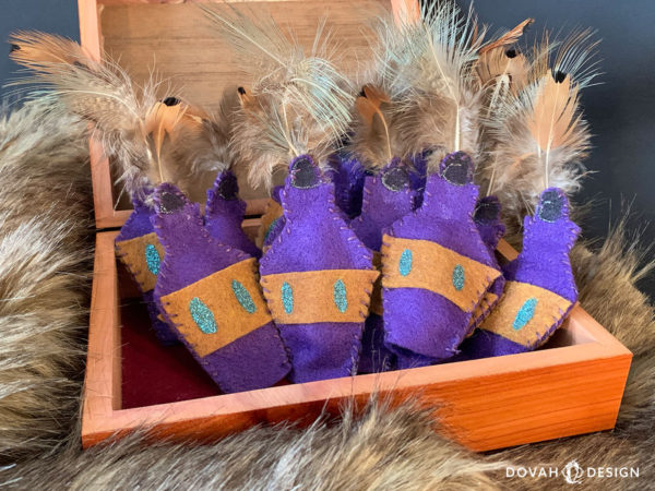 Box of handmade skooma bottle cat toys, posed in an open box on top of fur blanket.