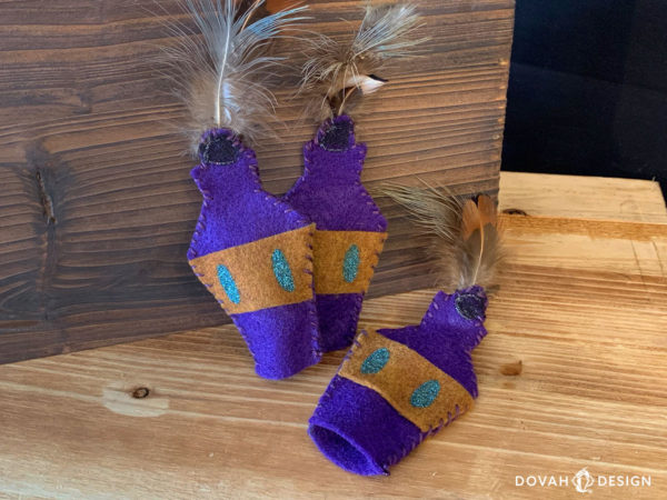 Three handmade cat toy skooma bottles posed on two wooden crates. Two bottles propped upright, one laying flat and showing open bottom for adding catnip.