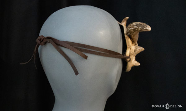 Handmade "bone dragon" masquerade mask, tied on to female bust, view from the back of brown leather laces tied around the mannequin head.