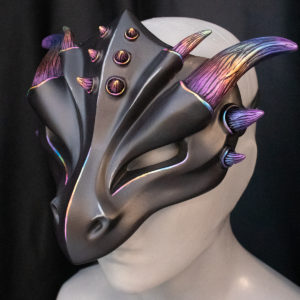 Black dragon mask with rainbow horns and matte finish, tied on mannequin bust, facing left.