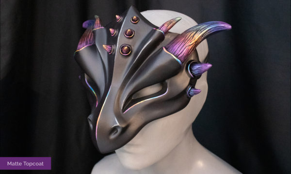 Black dragon mask with rainbow horns and matte finish, tied on mannequin bust, facing left.