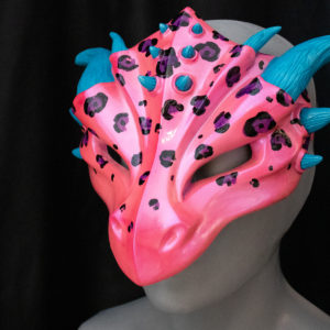 Hot pink and blue leopard spot dragon mask, inspired by Lisa Frank, facing left on black background, showing glossy hot pink finish.