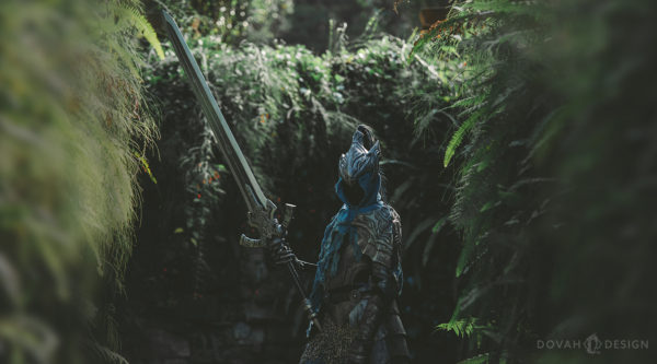 Sam in her Knight Artorias cosplay, holding the Greatsword of Artorias in a dark, green garden resembling Oolacile.