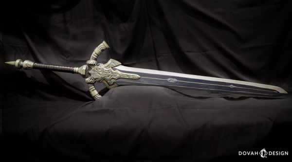Greatsword of Artorias replica prop, laying on it's side horizontally, full greatsword in frame with a black draped background.