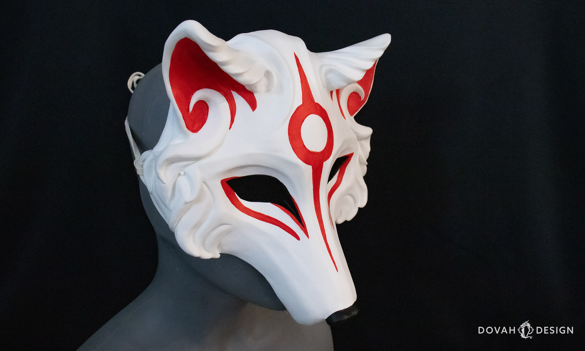 3/4 right view of the handmade Japanese-style Okami mask, cast in white resin with hand painted red details.